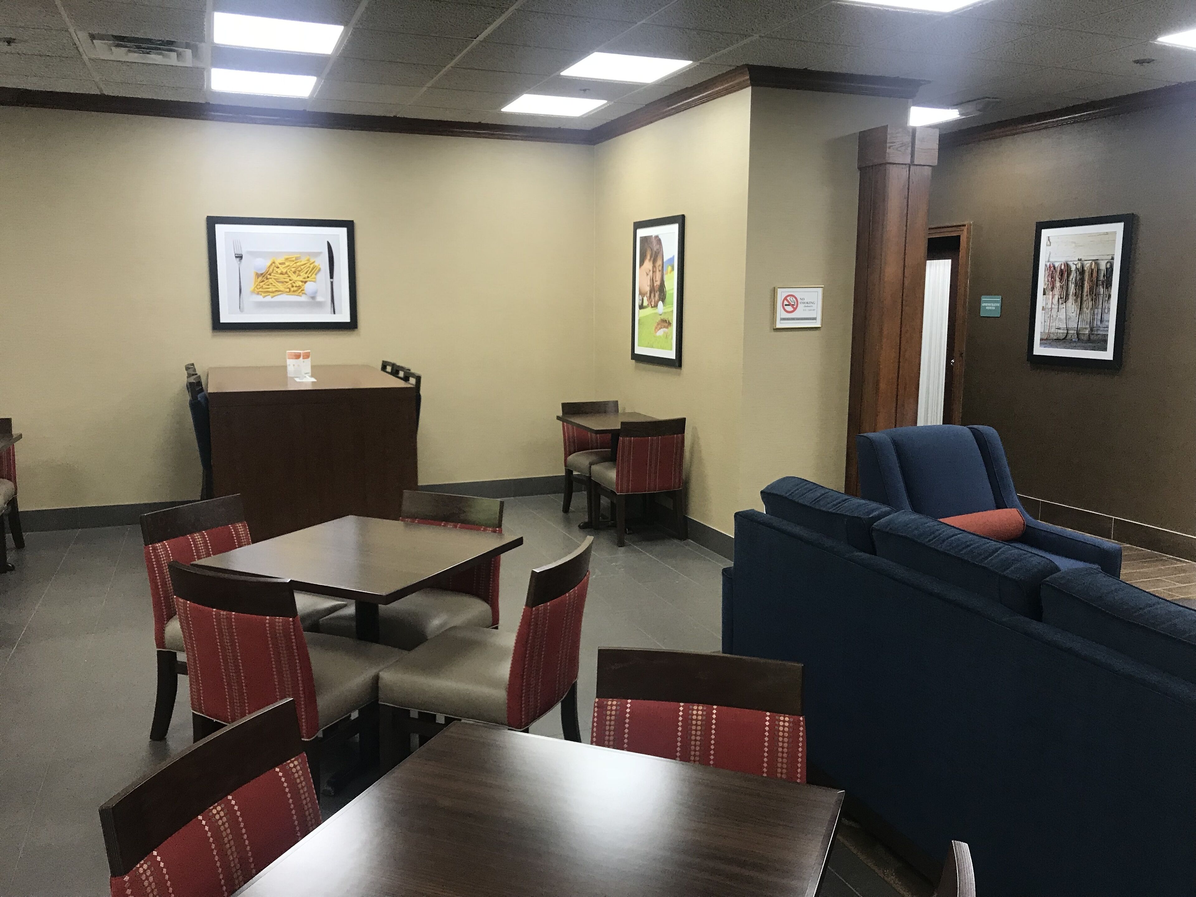 A hotel lobby with a reception desk, seating area, and framed pictures on the walls.