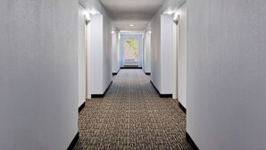A hallway with a patterned carpet, white walls, and recessed lighting. - Baymont by Wyndham Creedmoor (Creedmoor)