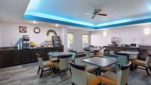 A modern restaurant with a blue ceiling, wooden flooring, and a variety of seating options including tables and chairs. - Baymont by Wyndham Creedmoor (Creedmoor)