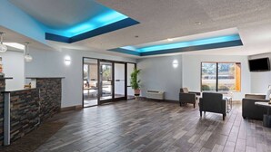 A spacious indoor area with a stone wall, a wooden floor, and a large window. - Baymont by Wyndham Creedmoor (Creedmoor)