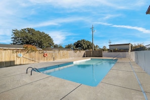 A rectangular swimming pool with a concrete deck, surrounded by a wooden fence and trees. - Red Roof Inn Washington, NC (Washington)