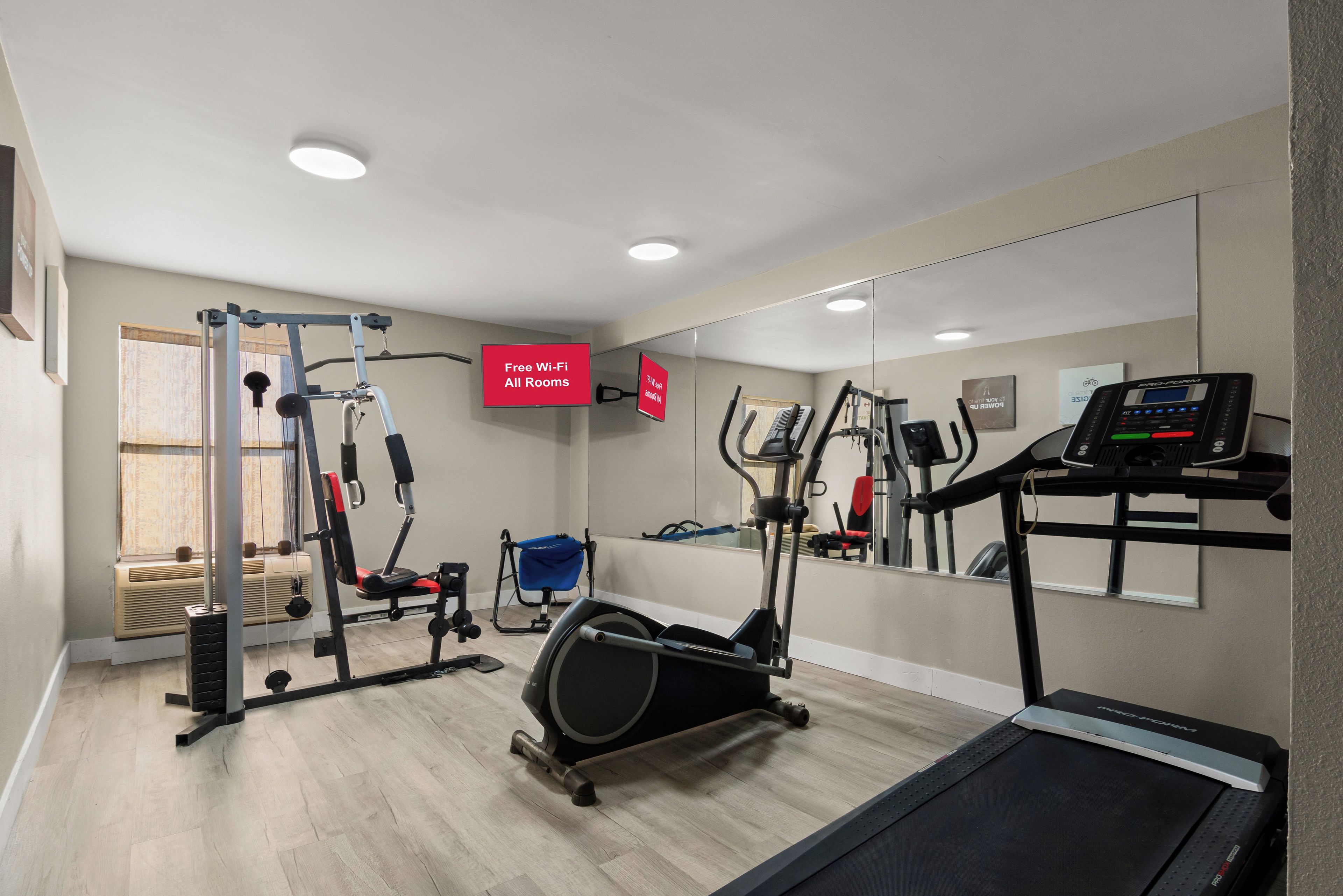 A gym with various exercise equipment, including a treadmill, elliptical, and weight machines.