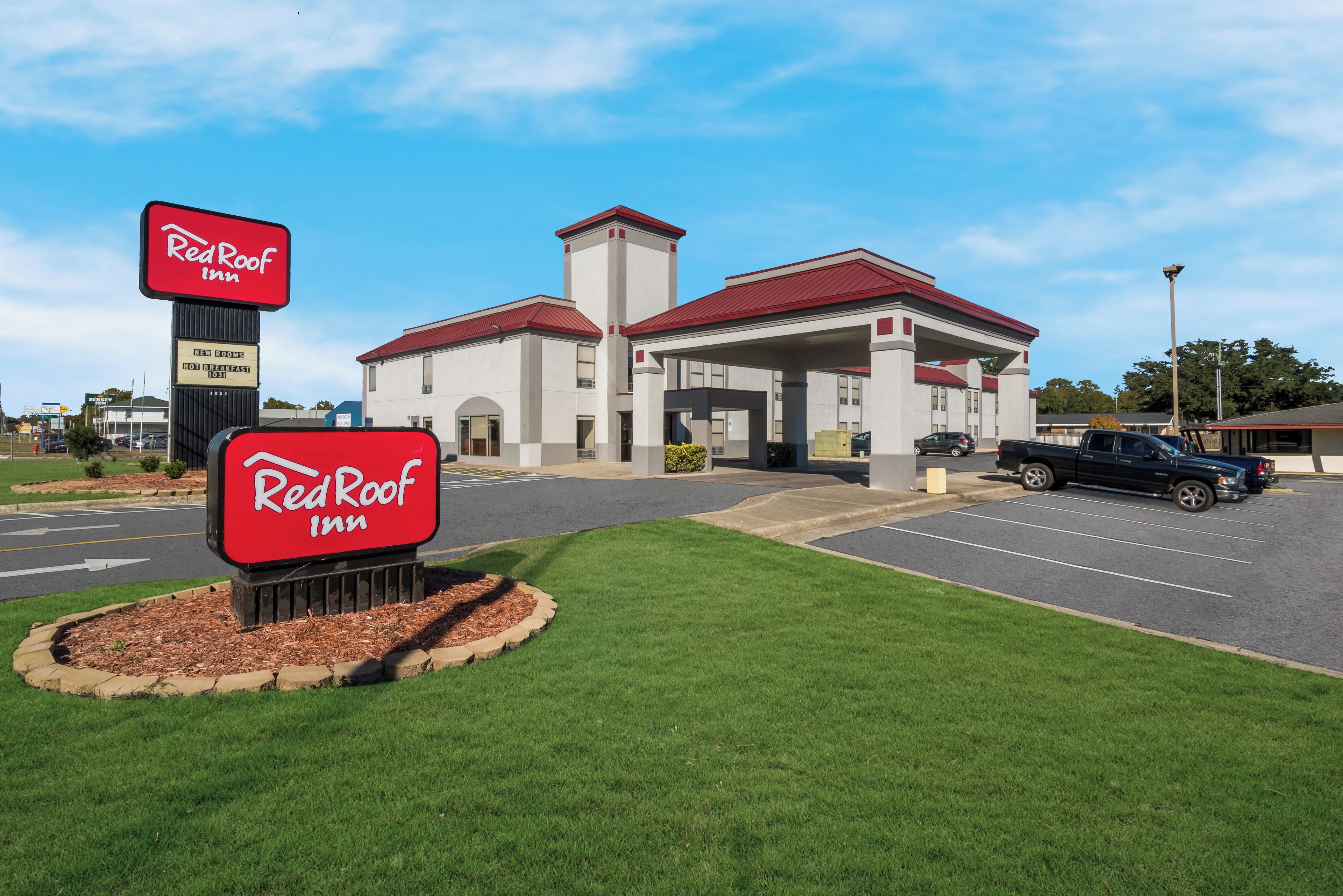 A Red Roof Inn with a parking lot and a building with a red roof.