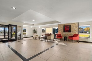 A hotel lobby with a reception desk, seating area, and a Red Roof Inn sign.