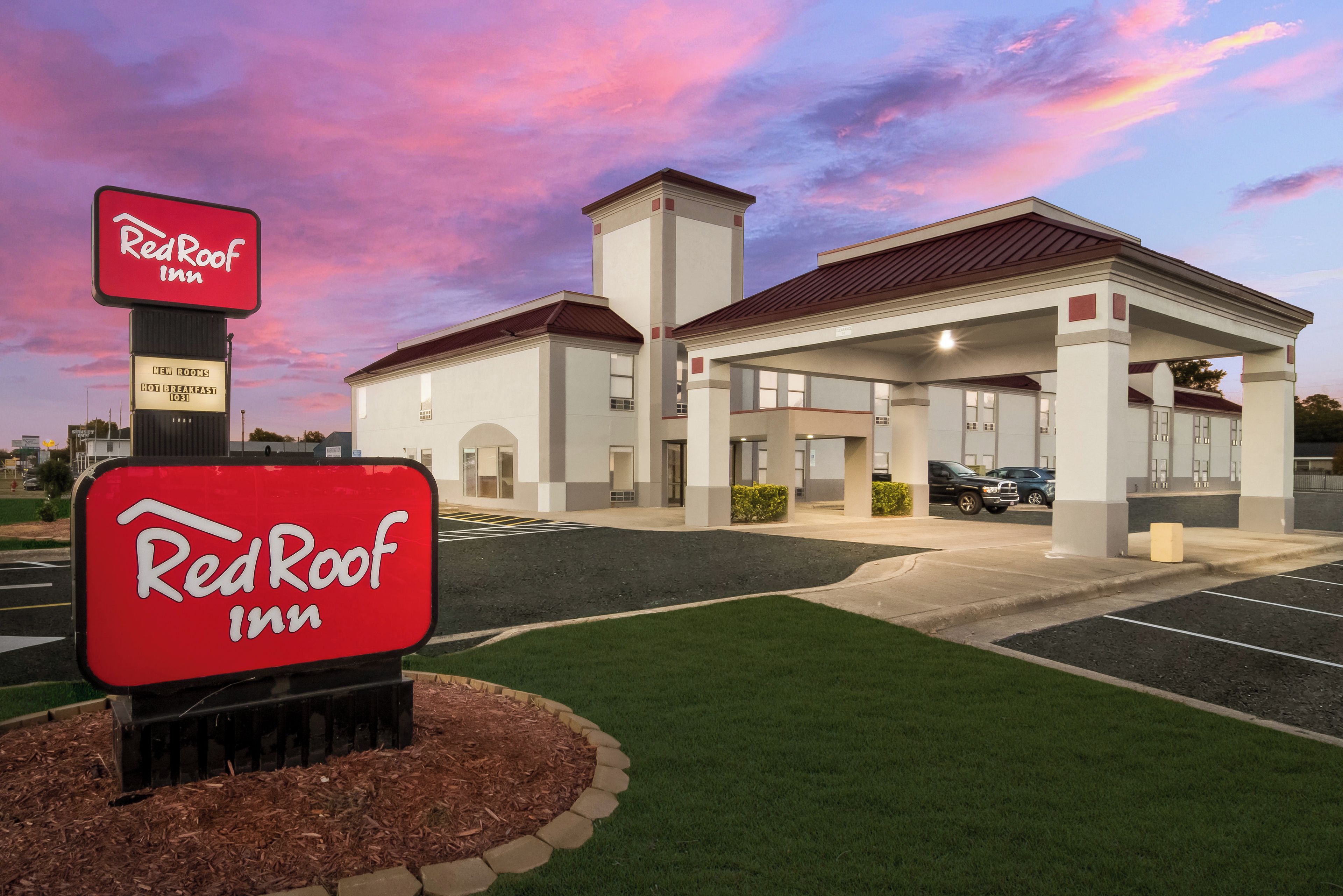 A Red Roof Inn with a sign indicating new rooms and hot breakfast.