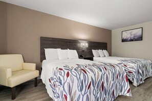 Quarto de hotel com duas camas, uma cadeira, uma mesa de cabeceira, um abajur e um quadro na parede.