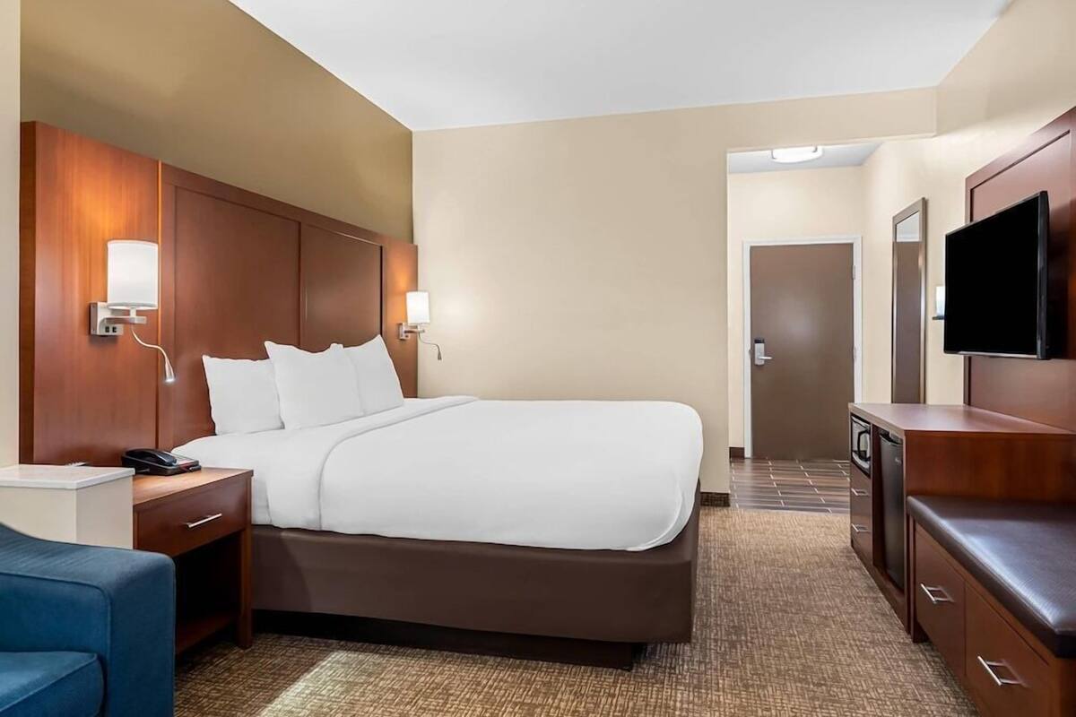 Ein Hotelzimmer mit Bett, Nachttischen, Schreibtisch, Stuhl, Fernseher und einer Tür.