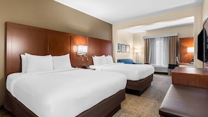 A hotel room with two large beds, a desk, a chair, a TV, and a window with curtains. - Comfort Suites near Camp Lejeune (Jacksonville)