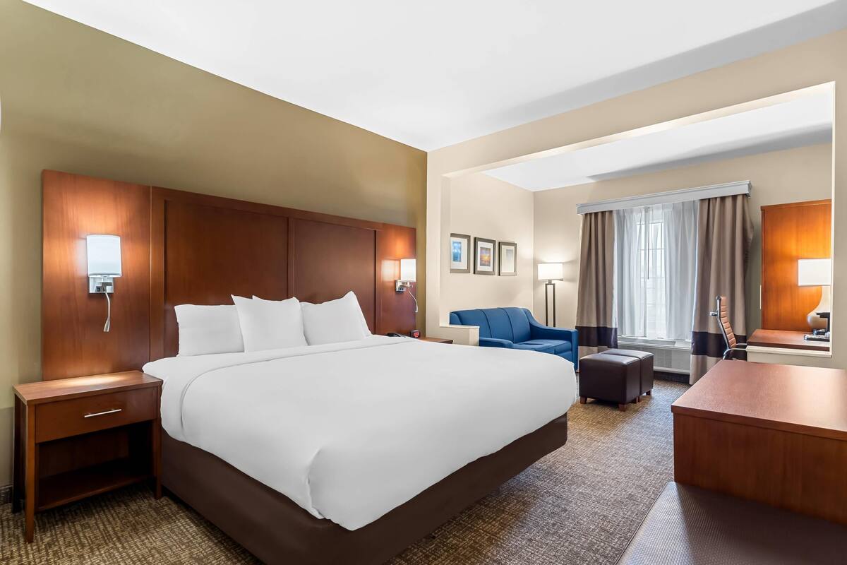 Ein Hotelzimmer mit einem großen Bett, einem Schreibtisch, einem Sessel und einer Couch.