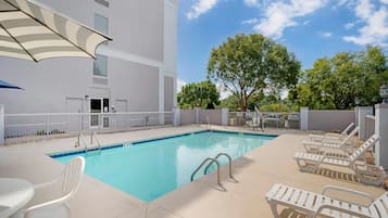 En säsongsöppen utomhuspool, parasoller och solstolar