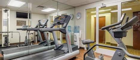 Um centro de atividades físicas com esteiras, bicicleta ergométrica e aparelho de musculação.