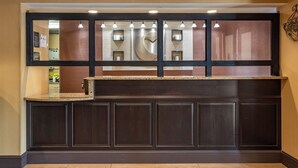 A reception area with a dark wood panel counter, a large mirror, and recessed lighting. - Comfort Inn Biltmore West (Asheville)