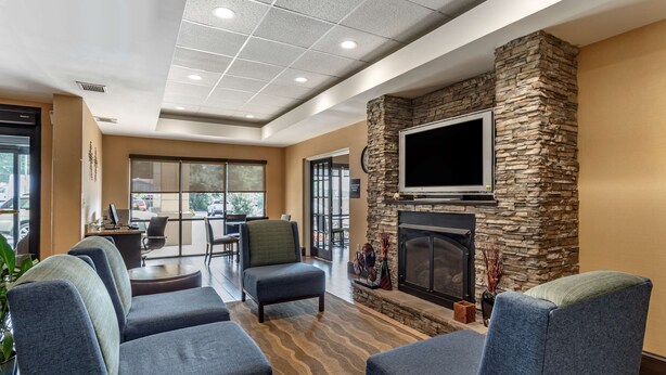 A modern lobby with a stone fireplace, comfortable seating, and a large TV screen. - Comfort Inn Biltmore West (Asheville)