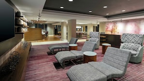 A modern lounge area with grey upholstered sofas, a wooden bench, and a red carpet.