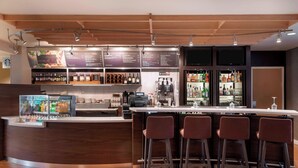 A modern bar area with a curved counter, bar stools, and a menu board displaying drink options.