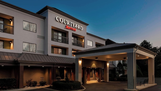 A Courtyard Marriott hotel with a covered entrance, multiple balconies, and a well-lit facade.