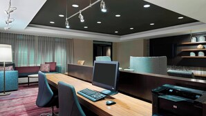 A modern office space with a wooden desk, computer, printer, and comfortable seating area.