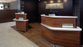 A reception area with a wooden reception desk and a smaller desk, both with white tops and metal bases.