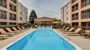A swimming pool with lounge chairs and a building with balconies in the background. - Courtyard Durham Near Duke University/Downtown (Durham)