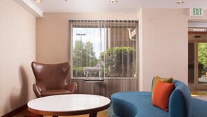 A modern hotel lobby with a round table, leather armchair, and blue sofa. - Fairfield Inn by Marriott Charlotte Gastonia (Gastonia)