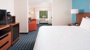 A hotel room with a bed, a television, a mini-fridge, a coffee machine, an orange chair, a window with curtains, and a lamp. - Fairfield Inn by Marriott Charlotte Gastonia (Gastonia)