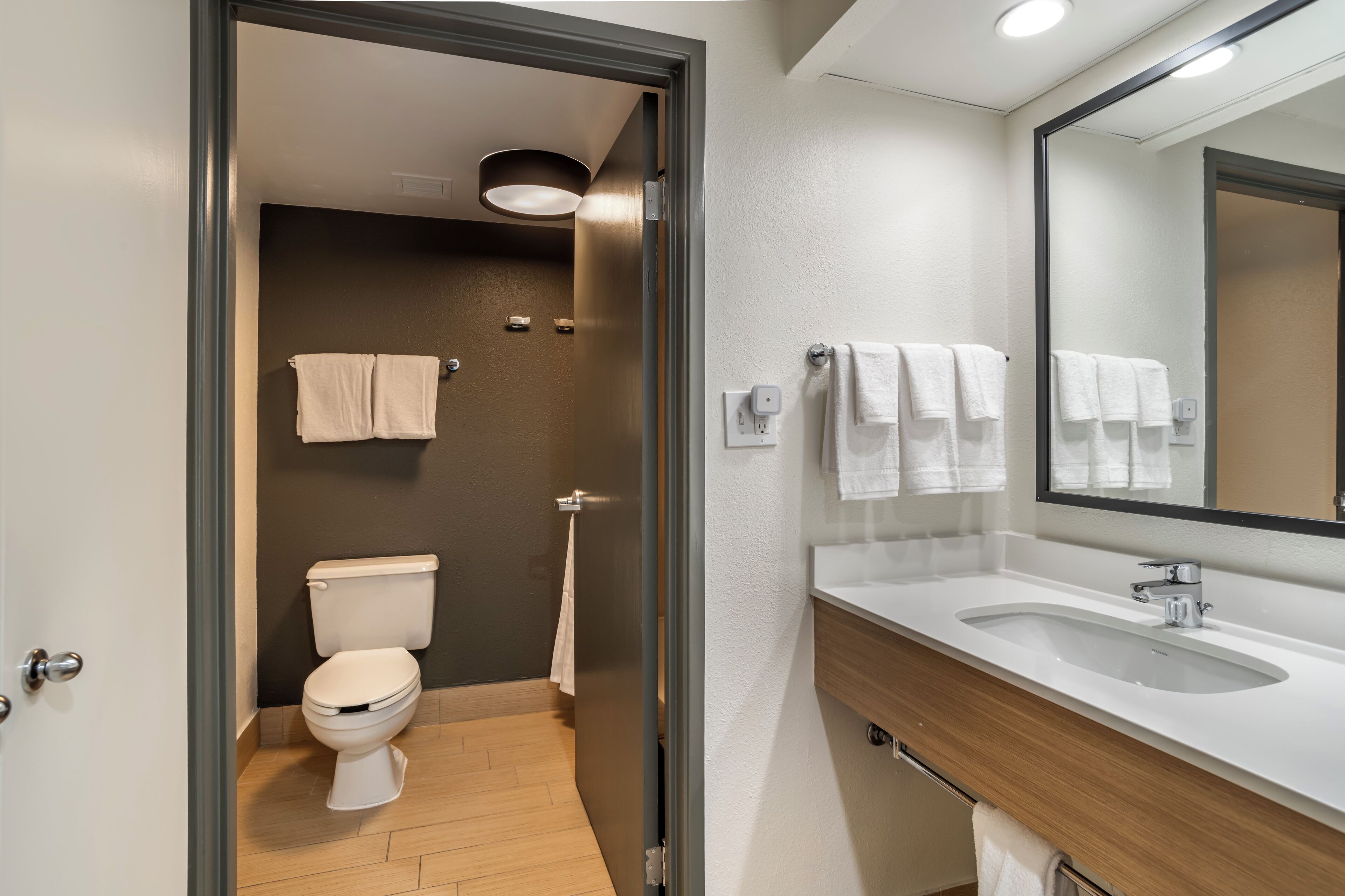 Un bagno moderno con il water, un lavandino e uno specchio.