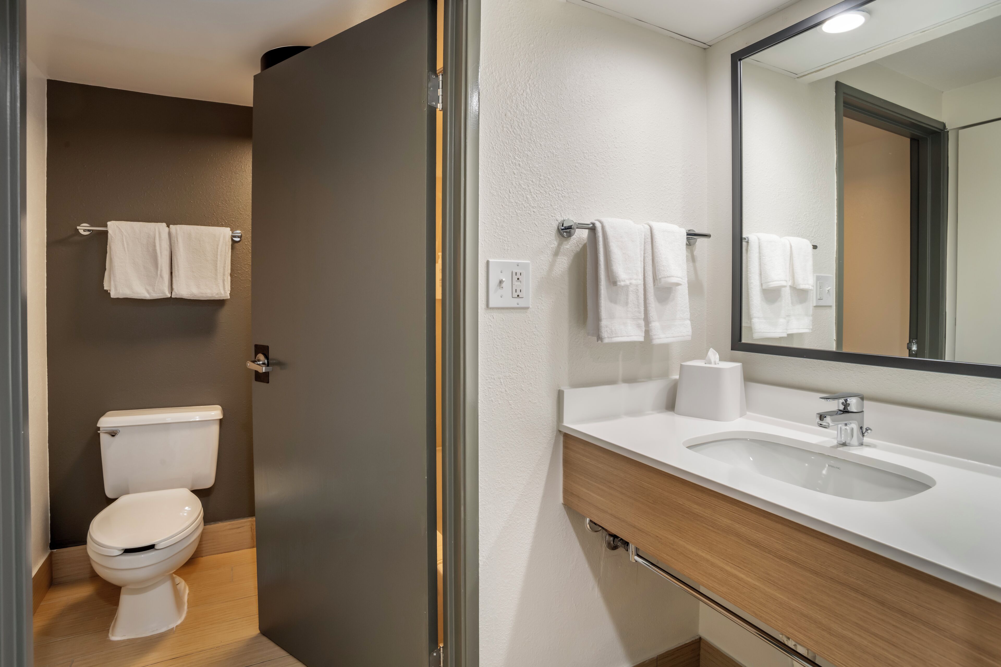 A modern bathroom with a toilet, sink, and mirror.