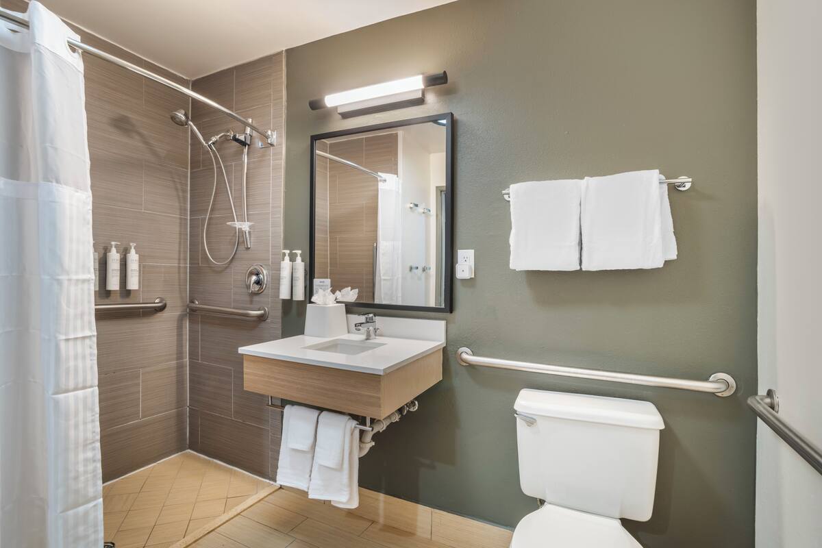 A modern bathroom with a shower, sink, and toilet.