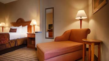 A hotel room with a bed, a sofa, two bedside tables with lamps, a mirror, and a dresser.
