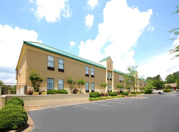 A two-story hotel with a green roof, multiple windows, and a parking lot.