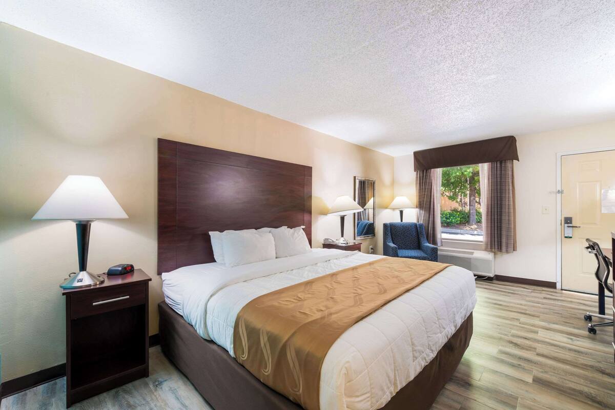 Ein Hotelzimmer mit einem großen Bett, Nachttischlampen, einem Schreibtisch und einem Sessel.
