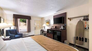 A hotel room with a bed, a desk with a chair, a television, a microwave, and a coffee maker.