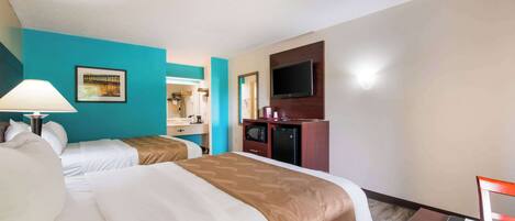 A hotel room with two beds, a desk, a TV, and a mirror.