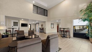 A spacious lobby with a high ceiling, modern furniture, and a large window overlooking a balcony. - Quality Inn & Suites Matthews - Charlotte (Matthews)