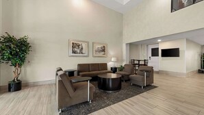 A spacious lobby with a sofa, armchairs, a coffee table, and a potted plant. - Quality Inn & Suites Matthews - Charlotte (Matthews)