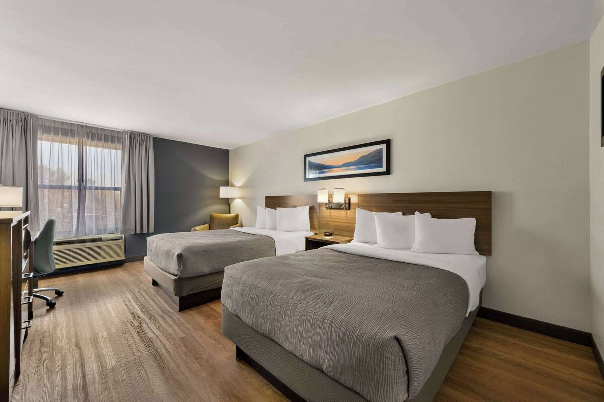 Habitación de hotel con dos camas, un escritorio y una silla.