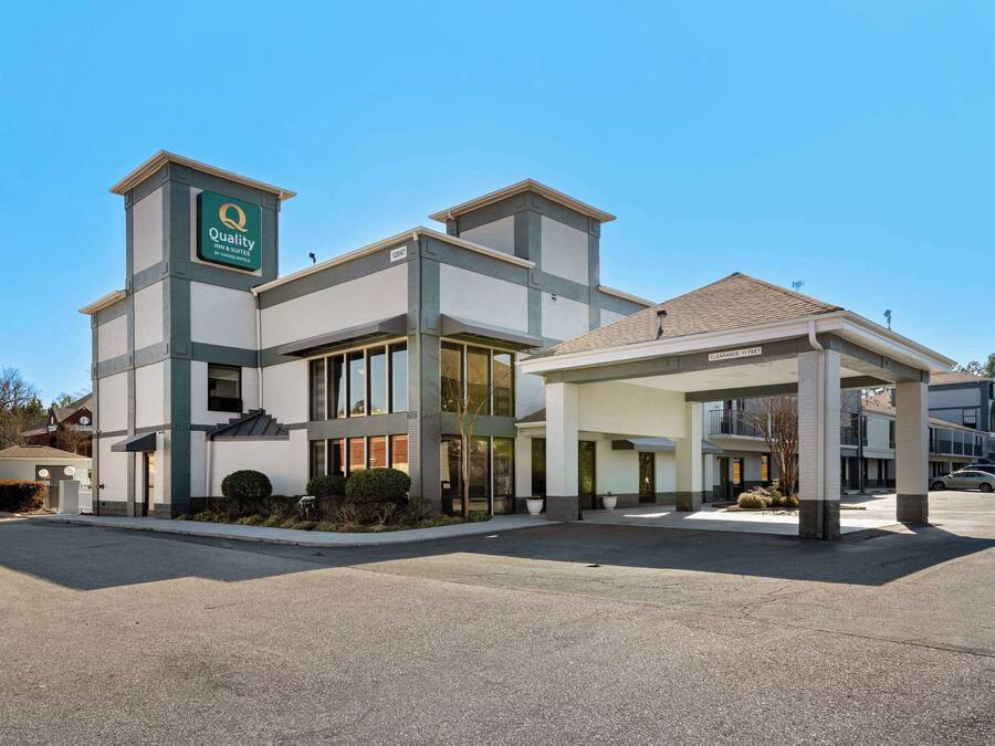 Een modern hotel met een opvallend bord, een overdekte ingang en een parkeerplaats.