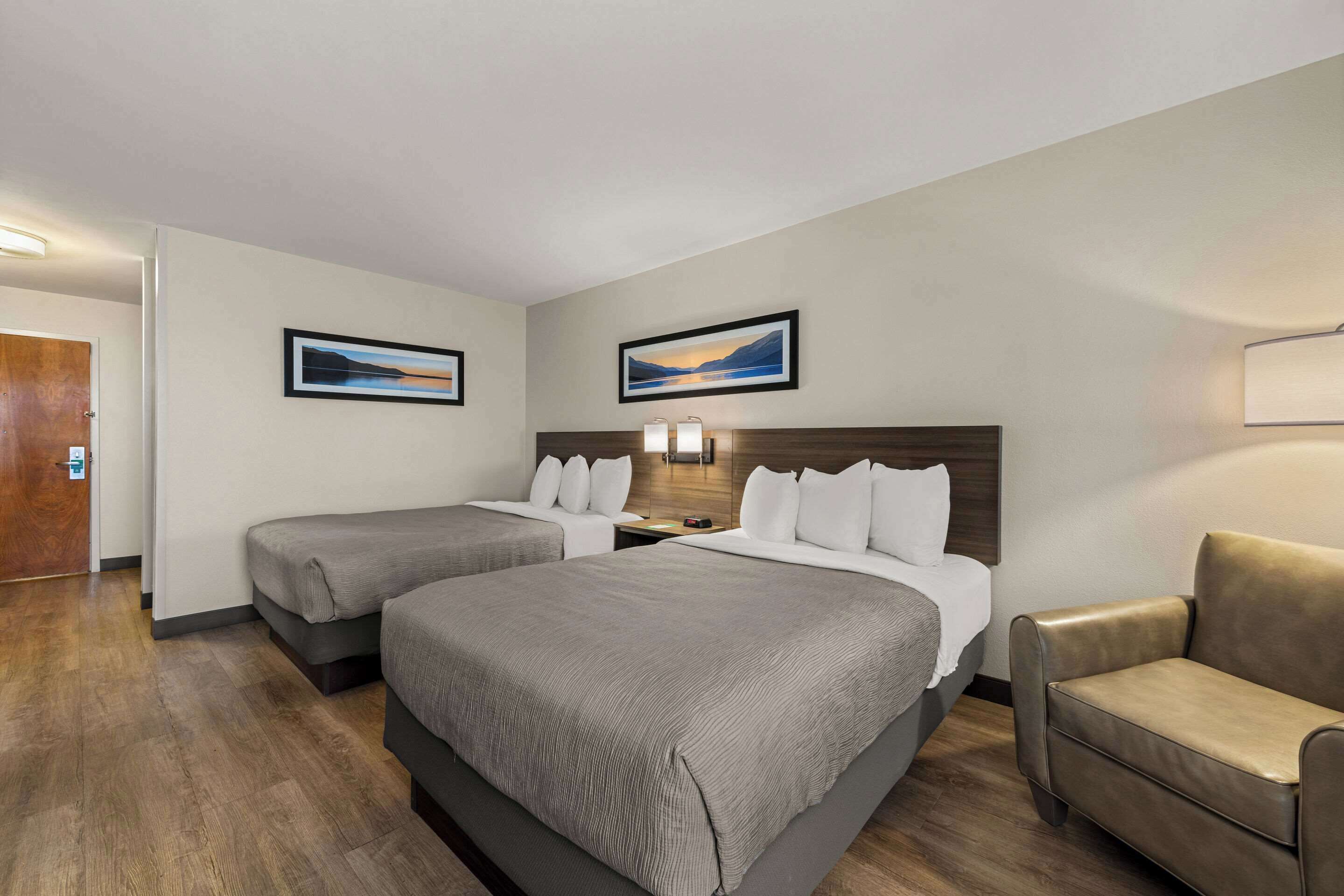 Ett hotellrum med två sängar, en soffa och två inramade tavlor på väggen.