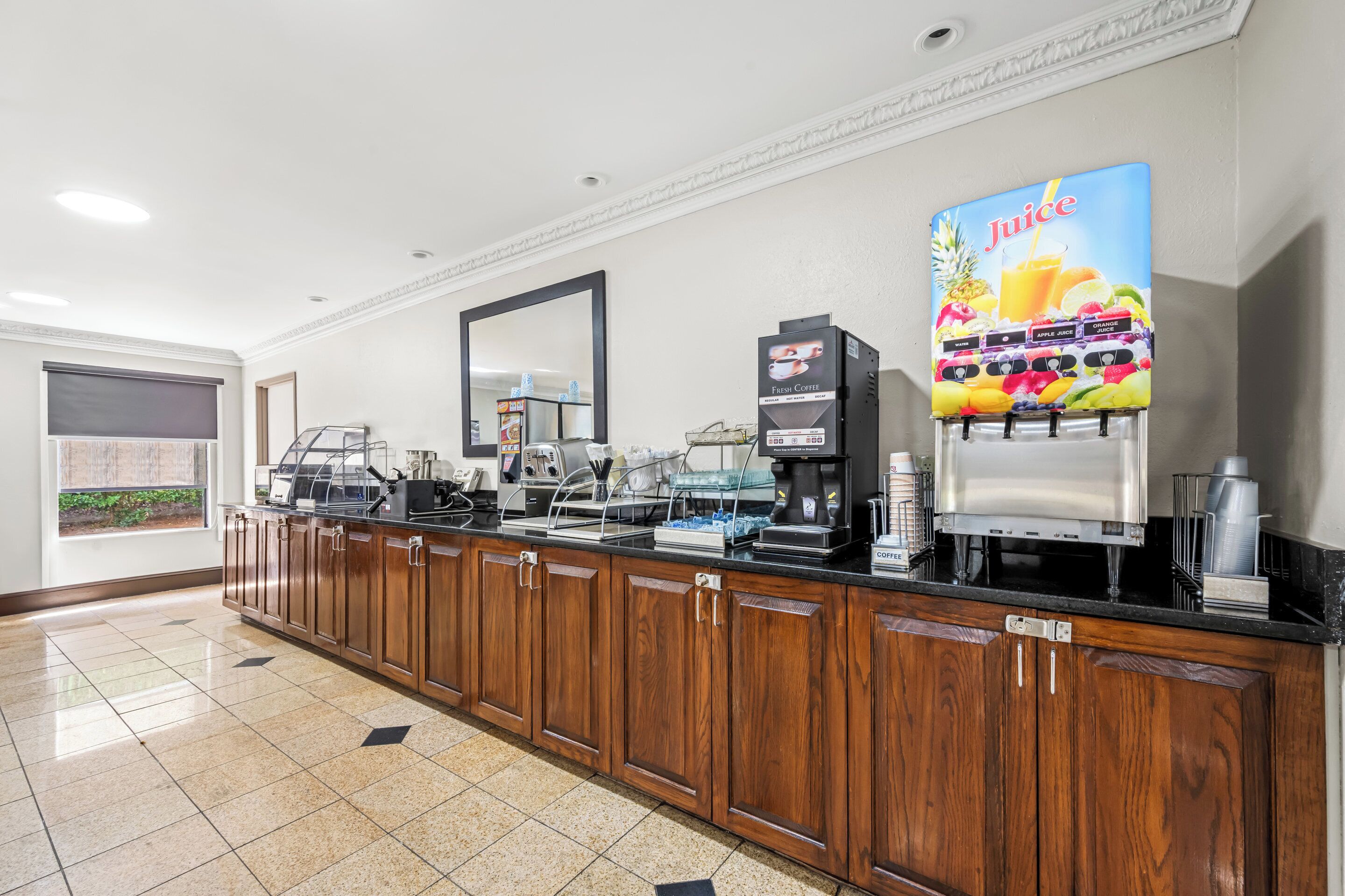 Un espace de libre-service où l'on peut se servir des boissons, avec des machines à café, un distributeur de jus et une machine à café.