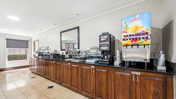 Un espace de libre-service où l'on peut se servir des boissons, avec des machines à café, un distributeur de jus et une machine à café.