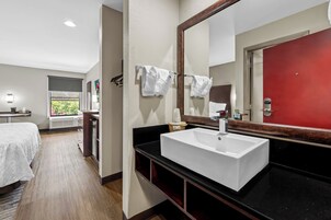 Un baño de hotel con un lavamanos blanco, un espejo grande y una puerta roja.