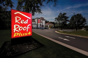 A Red Roof Plus sign with a building in the background. - Red Roof Inn PLUS+ Henderson (Henderson)