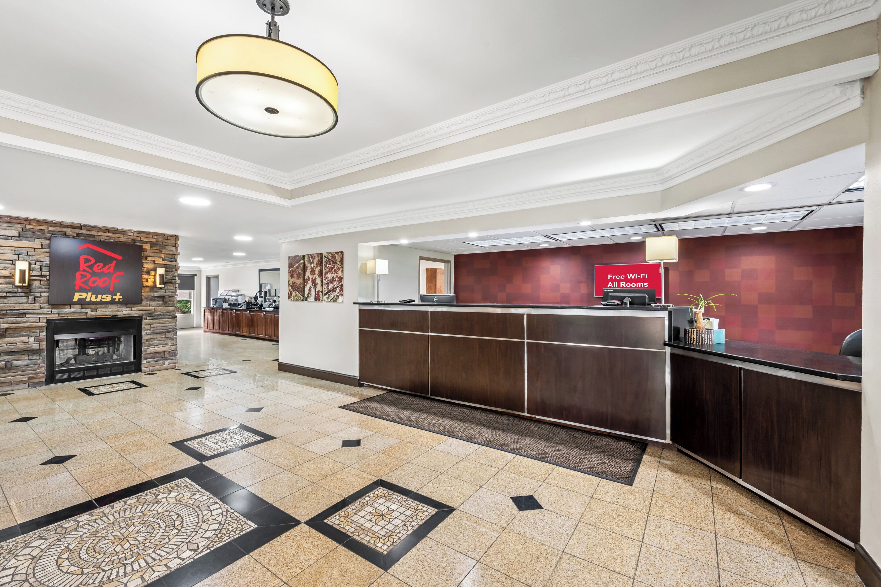 A hotel lobby with a reception desk, a fireplace, and a sign indicating free Wi-Fi availability.