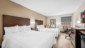 A hotel room with two beds, a desk, a chair, and a TV.