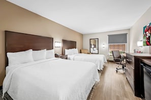 Une chambre d’hôtel avec deux lits, un bureau, une chaise et un téléviseur.