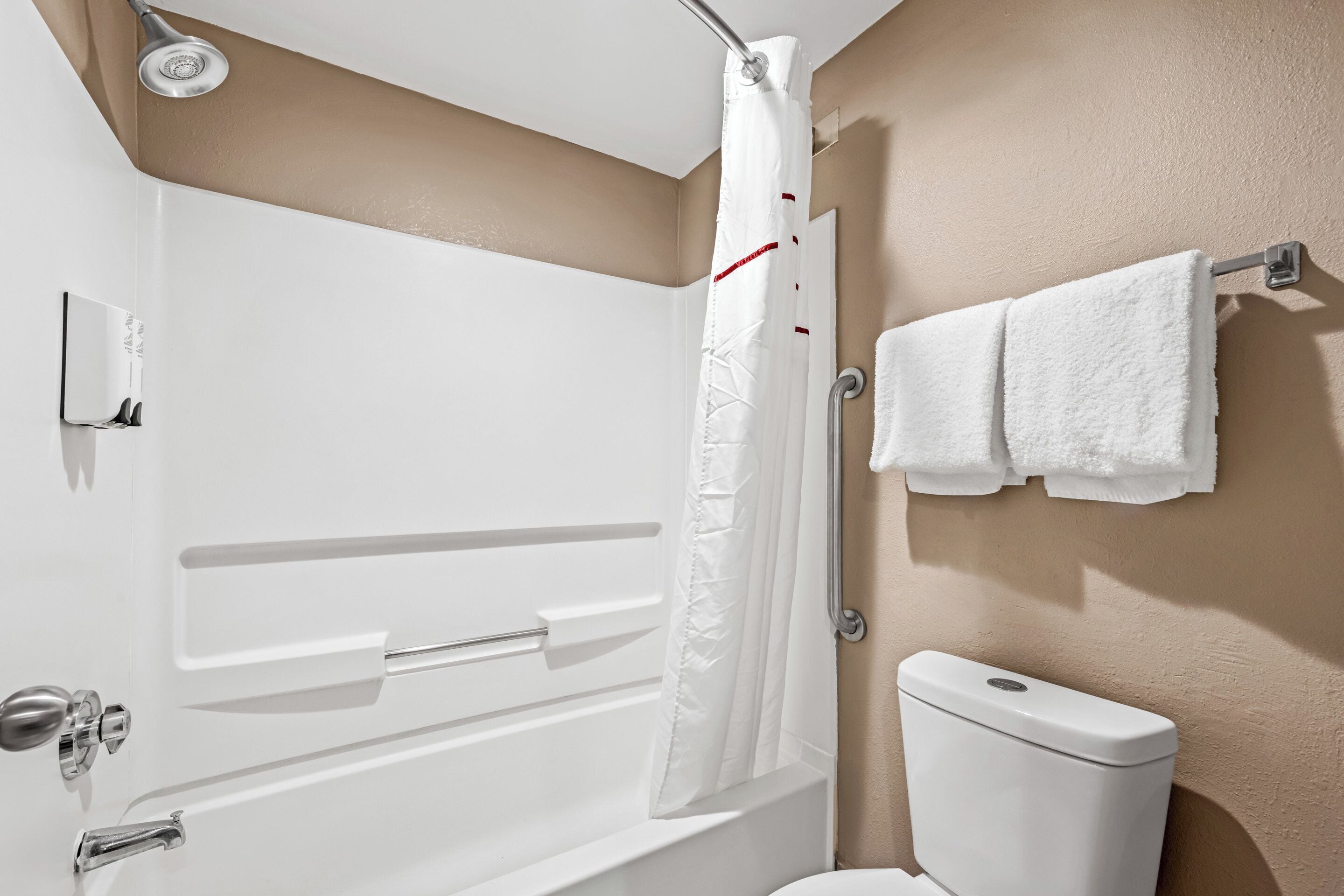 Un baño con una bañera blanca, cortina de ducha, inodoro y un perchero para toallas.
