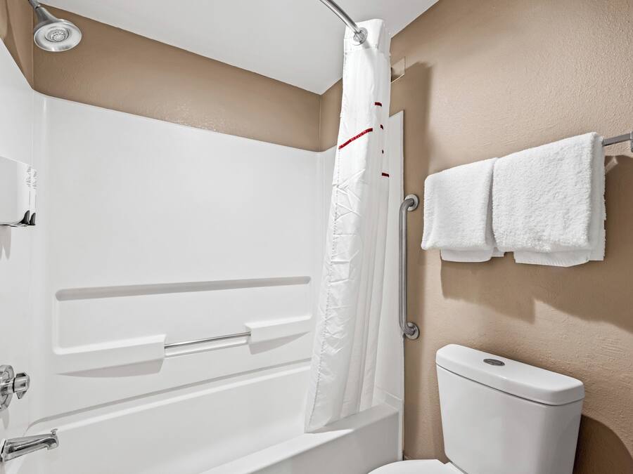 A bathroom with a white bathtub, a shower curtain, a toilet, and a towel rack.