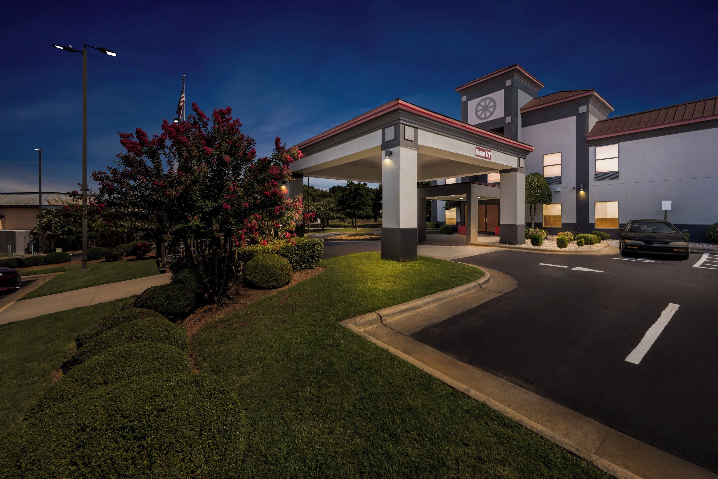 A hotel entrance with a gas station, well-maintained landscaping, and a clear sky.