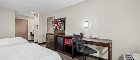 A hotel room with two beds, a desk with a chair, a microwave, a TV, and a heater.