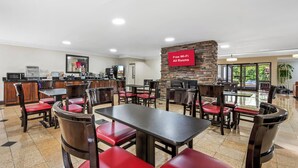 A restaurant with a stone wall, red cushioned chairs, and a flat-screen TV displaying 'Free Wi-Fi All Rooms'.